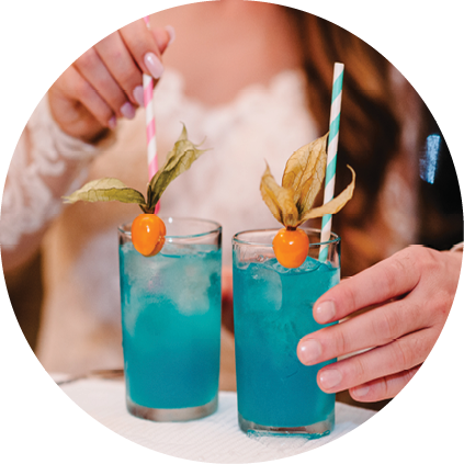 The bride and groom holding a colorful cocktail in her hand  Man and woman hand hold fresh blue juice in the glass on the bar counter at night club in wedding day 