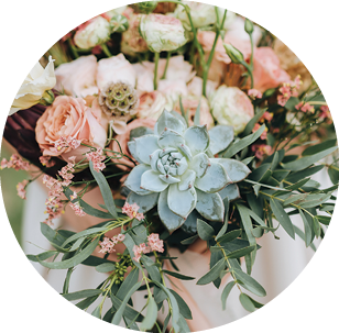 bride in a dress standing in a green garden and holding a wedding bouquet of flowers and greenery