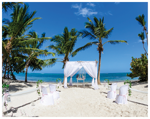 Colorful wedding arch gazebo pavilion made of bamboo and textile with fresh flowers decoration at sandy beach on sunny day for destination wedding ceremony in Dominican republic 