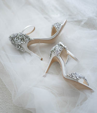 White shoes of the bride in brilliant crystals lie on the veil. Things for an elegant wedding.