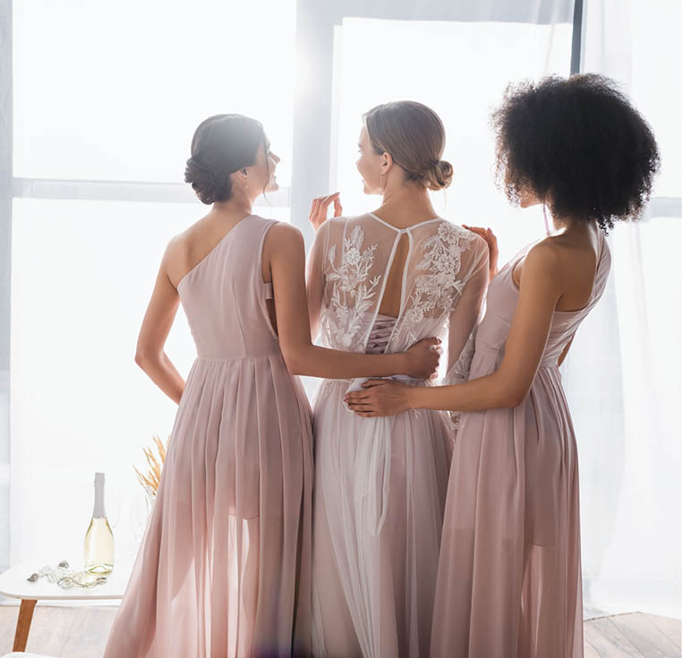elegant bridesmaids hugging young bride on sunny morning at home