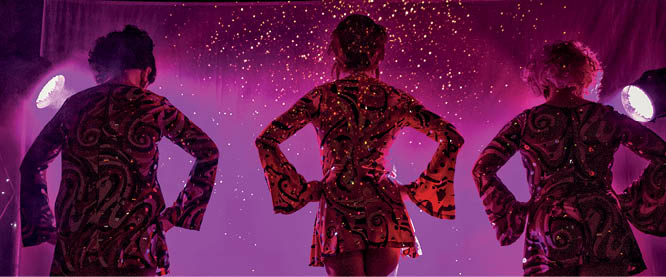 trio of female performers on stage about to begin their act