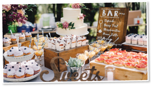 Candy bar  White wedding cake decorated by flowers standing of festive table with deserts, strawberry tartlet and cupcakes  Wedding  Reception