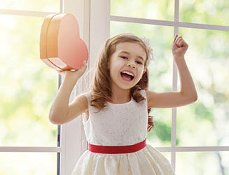 Sweet child girl with red heart  Little girl dancing on the window and holding gift box  Wedding, Valentine concept 
