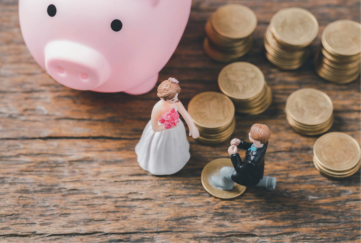 Save money for wedding and planning wedding concept. Sustainable financial goal for family life or married life. Miniature wedding on rows of rising coins, depicts savings or growth for new family.