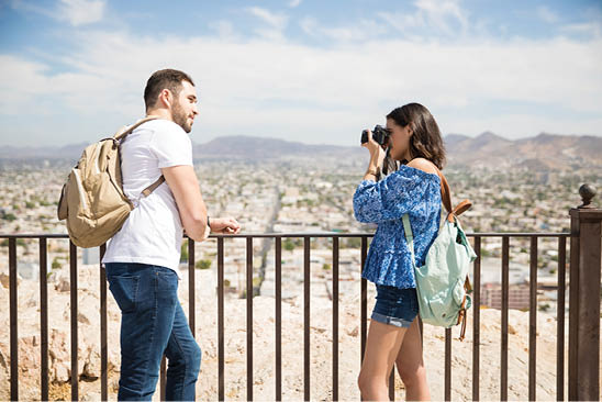 Pretty woman clicking boyfriend photos using camera while traveling 