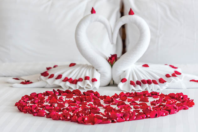 White two towel swans and red rose on the bed in Honey moon suit