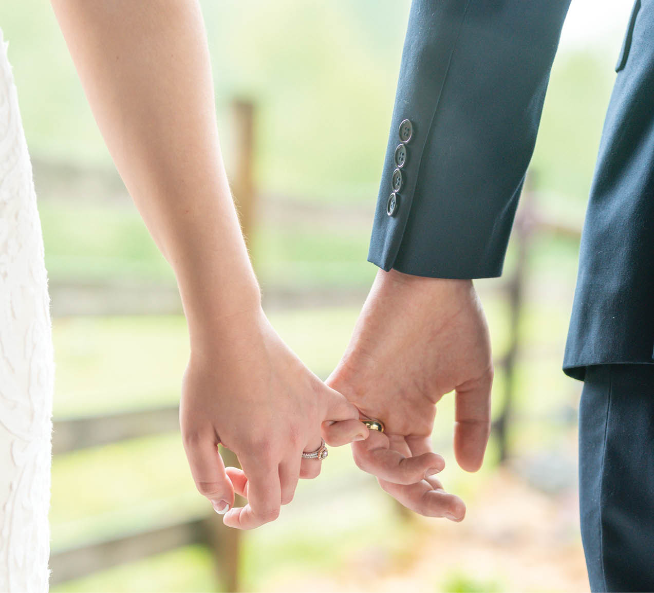 A vertical shot of a bride and a groom holding hands in a garden