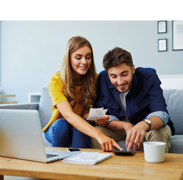 Happy young couple paying bills together and managing budget, sitting on the sofa and using calculator and laptop