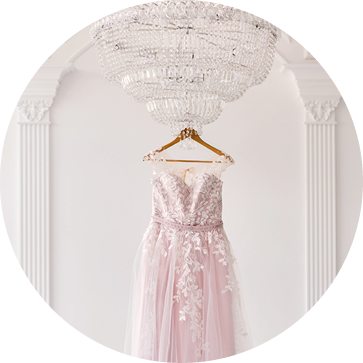 Rich pink wedding dress hangs on a chandelier in a white room