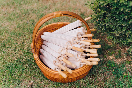Paper umbrellas in a straw basket at a summer wedding on a hot day