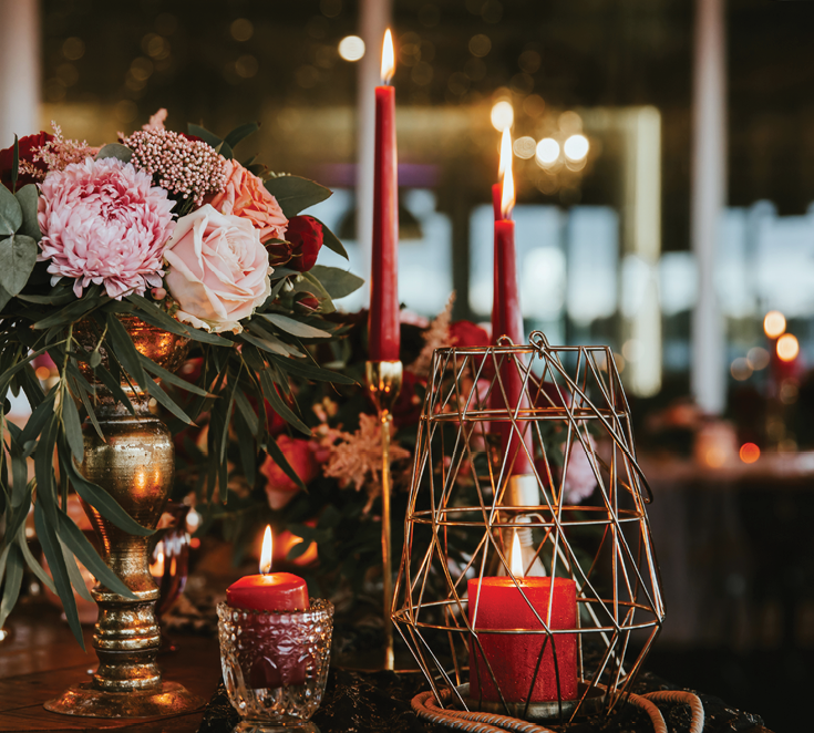 Beautiful, decorated table with flower decorations and red candles. Christmas evening or wedding party decoration.
