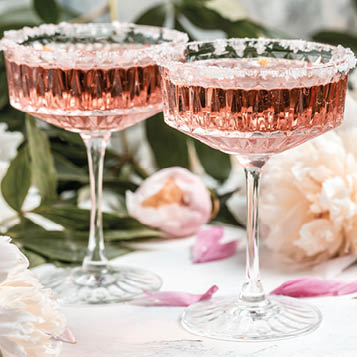 Rose wine in glass and peony flowers over white background, Summer celebration, wedding greeting card, invitation concept.