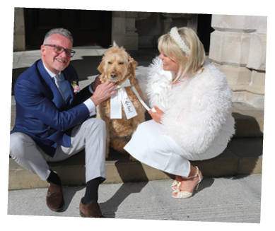 A man and woman sitting on steps with a brown dog. Description generated by AI