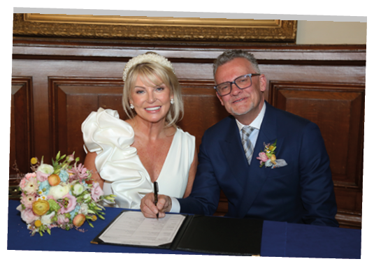 A man and woman are signing a book together. Description generated by AI