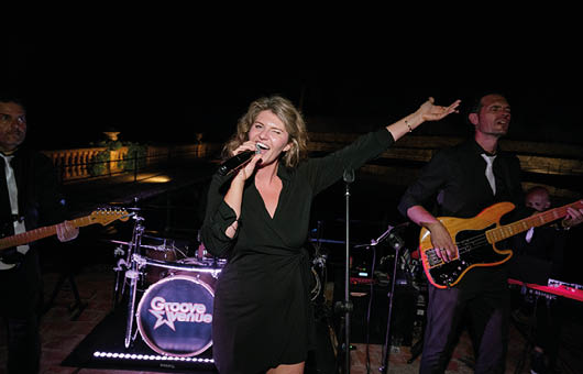 A woman wearing a black dress and singing into a microphone. Description generated by AI