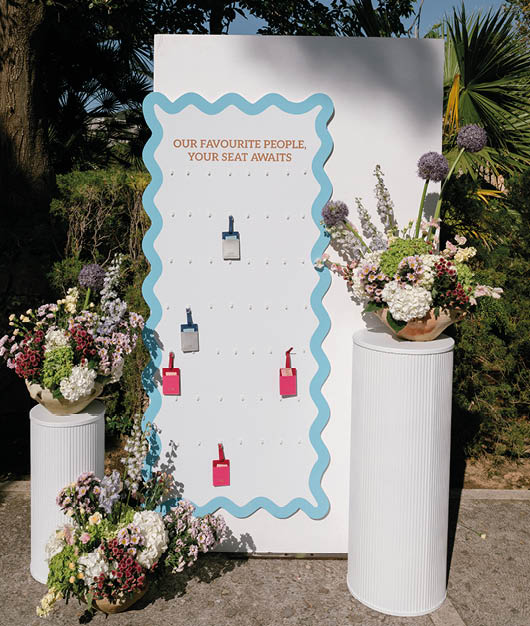 A white sign with blue stripes and a row of pink bottles. Description generated by AI