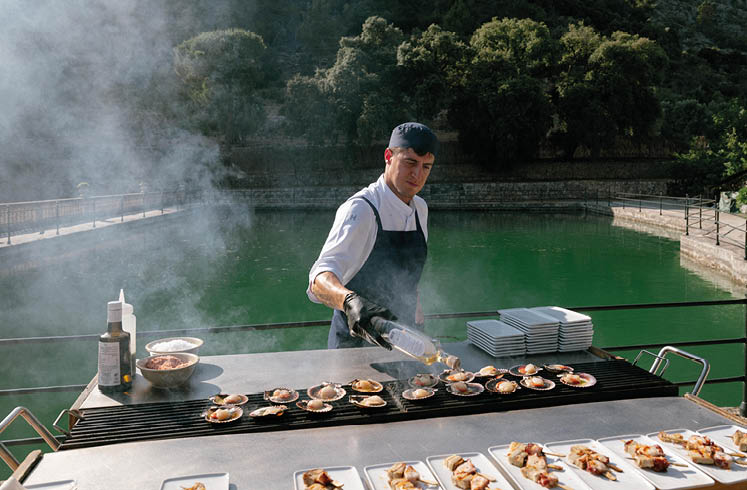 A man cooking food on a grill. Description generated by AI