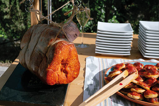 A table with a plate of food and a ham on a cutting board. Description generated by AI