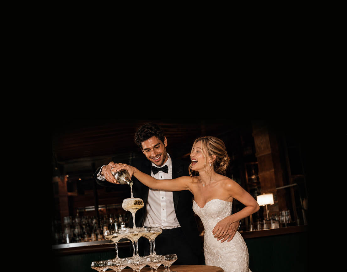 A man and woman are standing in front of a table with wine glasses. Description generated by AI