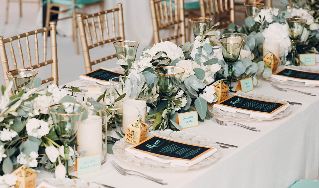 A table with a white tablecloth and a centerpiece of flowers and candles. Description generated by AI