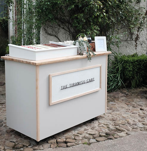 A small white desk with a sign that says “The Artisan Cafe" on it. Description generated by AI