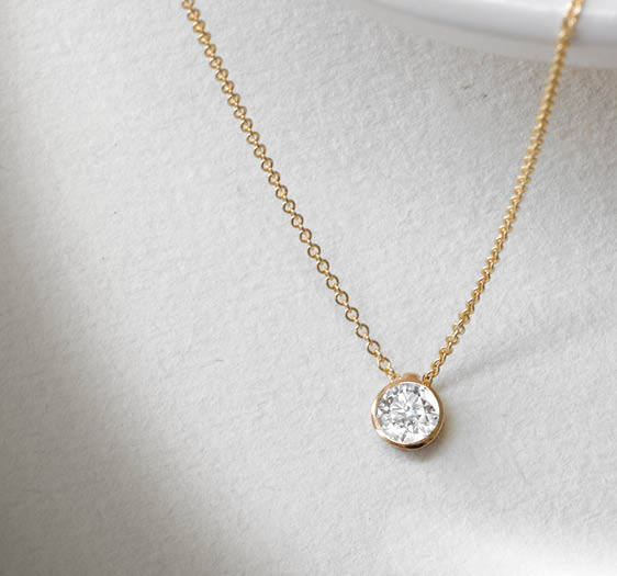 A gold necklace with a diamond pendant. Description generated by AI