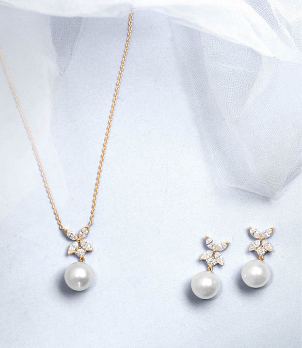 A gold chain with a pearl pendant and a pair of pearl earrings. Description generated by AI