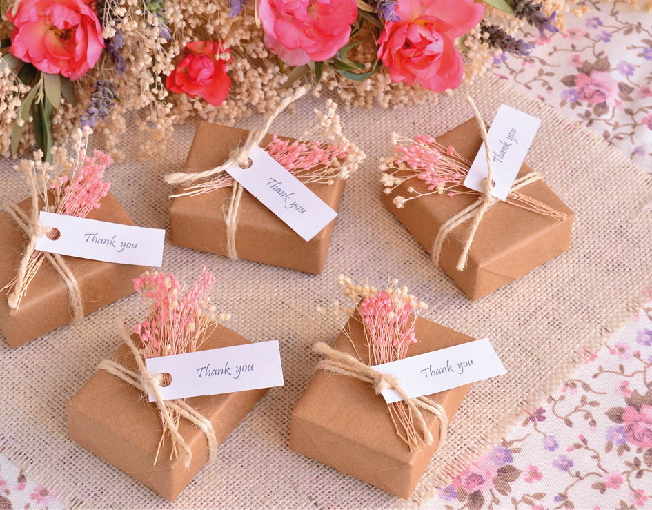 A collection of small brown boxes with ribbon and cards. Description generated by AI