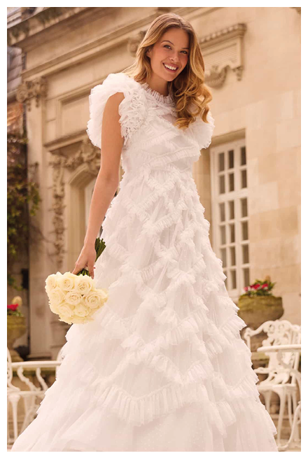 A woman wearing a white dress and carrying a bouquet of flowers. Description generated by AI