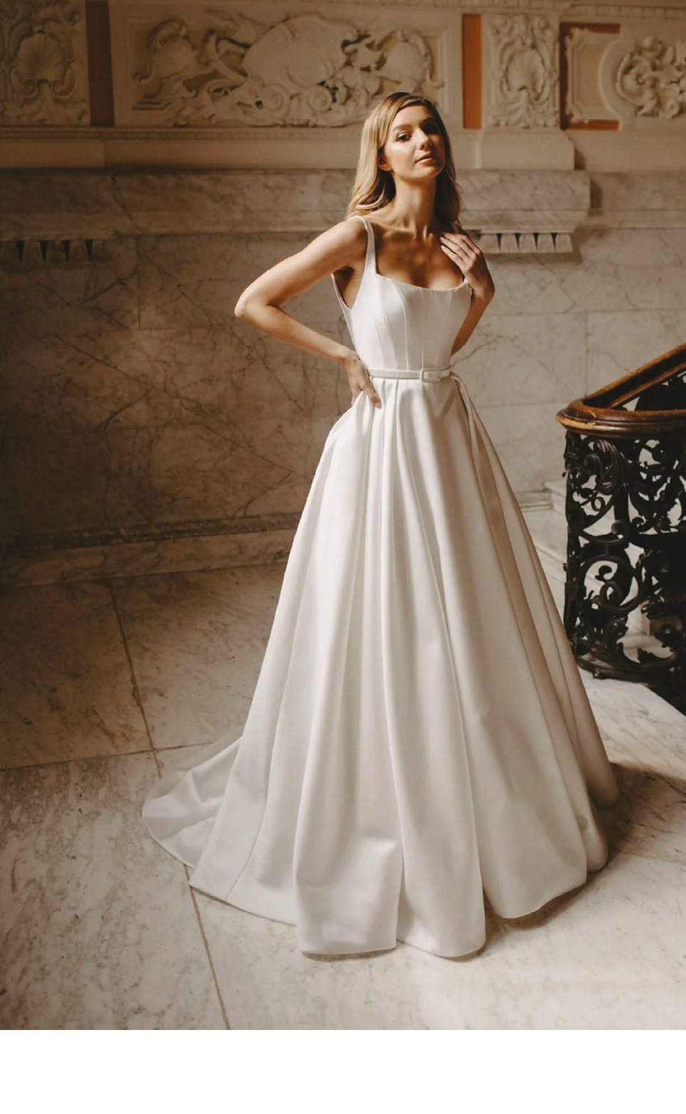 A woman in a white dress standing in front of a staircase. Description generated by AI
