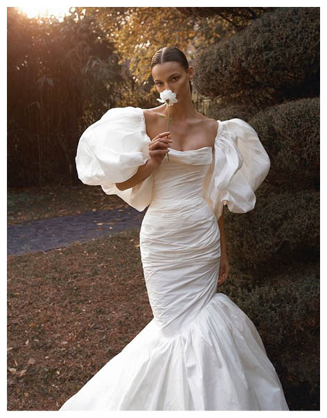 A woman wearing a white dress and holding a flower. Description generated by AI