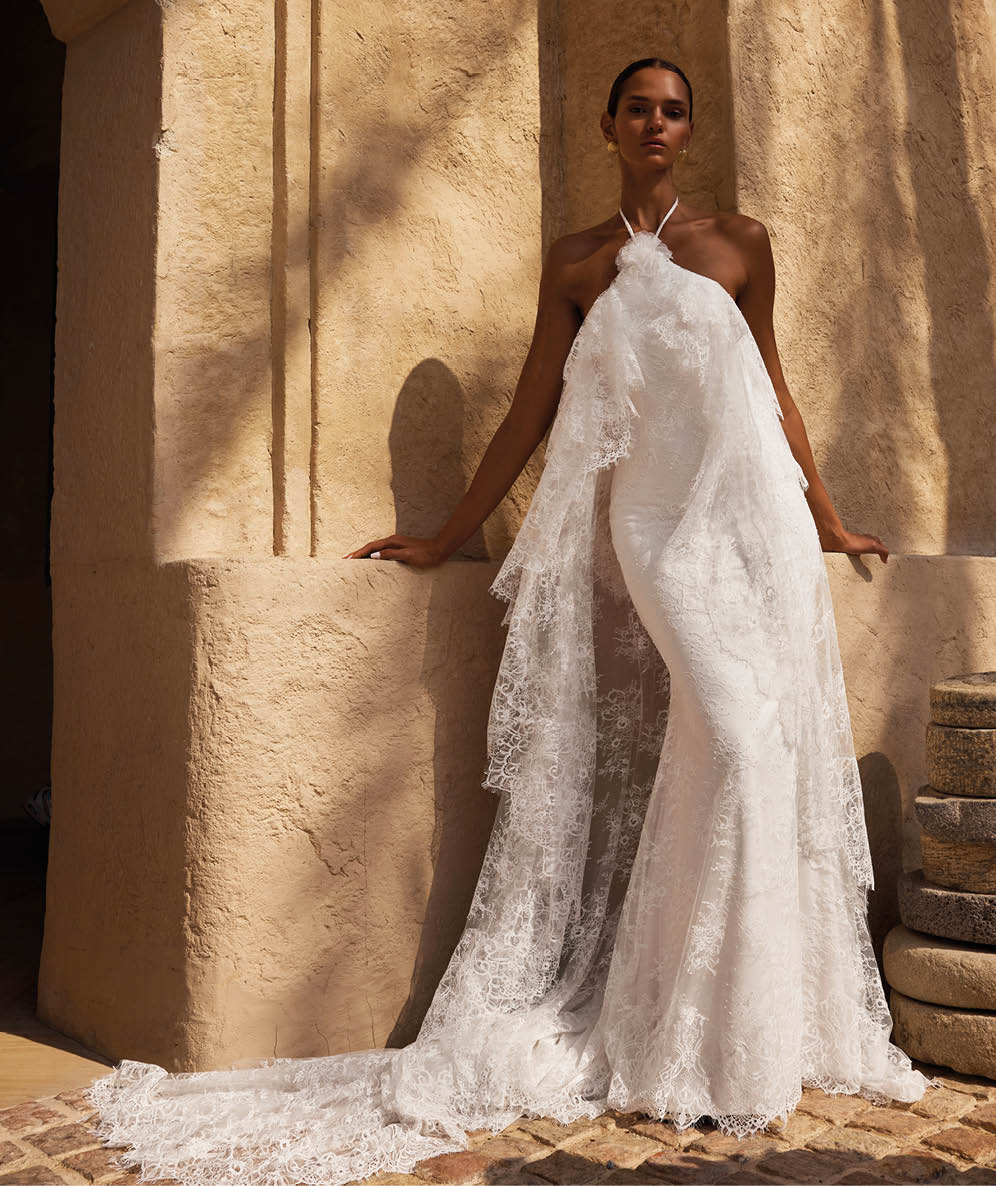 A woman in a white dress stands in front of a building. Description generated by AI