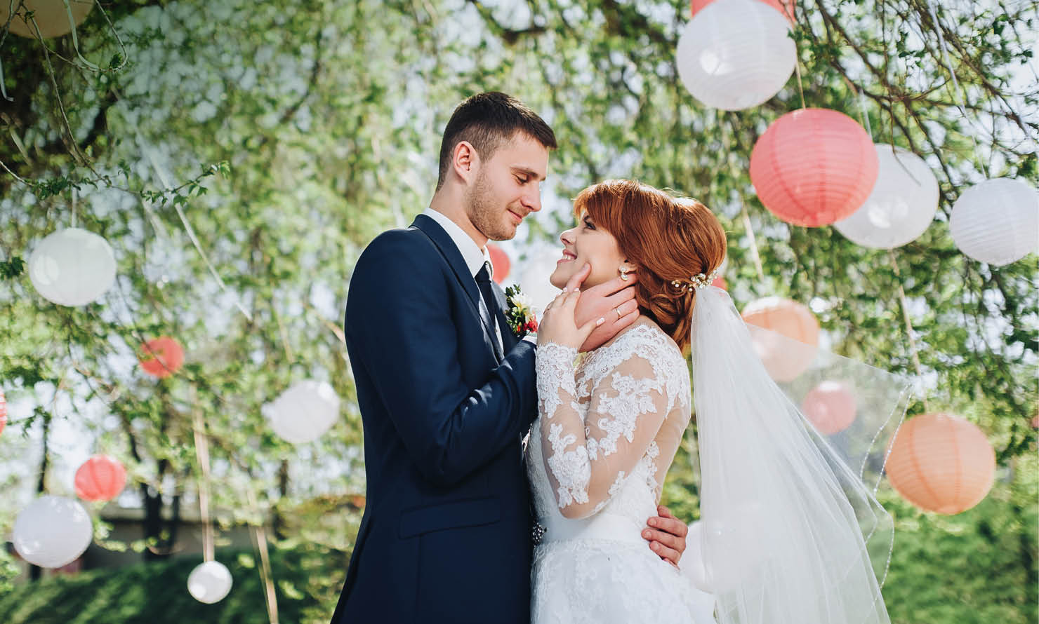 A bride and groom kissing under a tree with white lights in the background. Description generated by AI