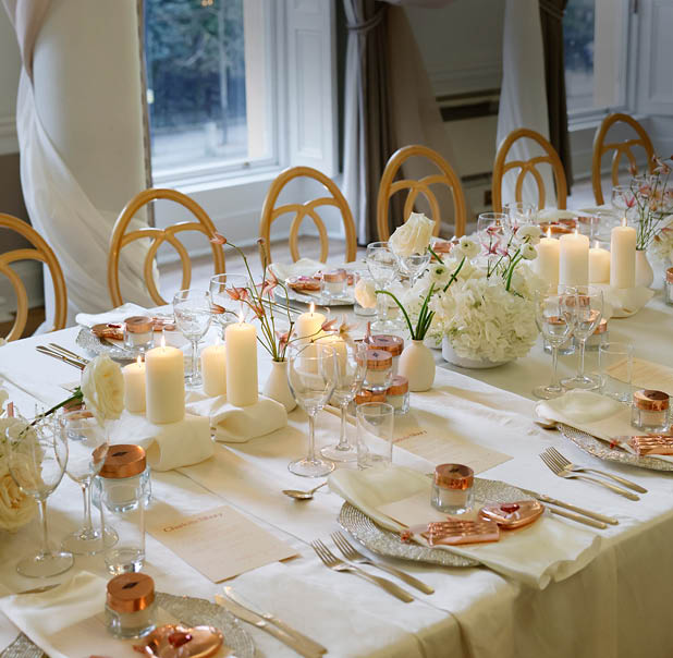A table set for a meal with white tablecloth, candles, and flowers. Description generated by AI