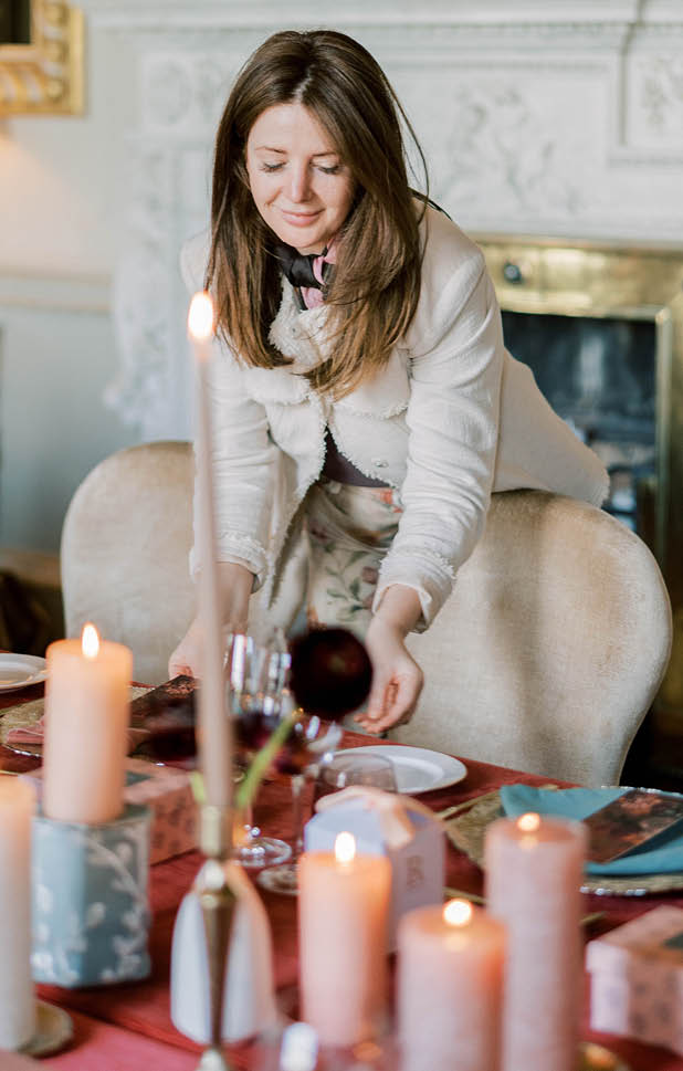 A woman sitting at a table with candles and wine glasses. Description generated by AI