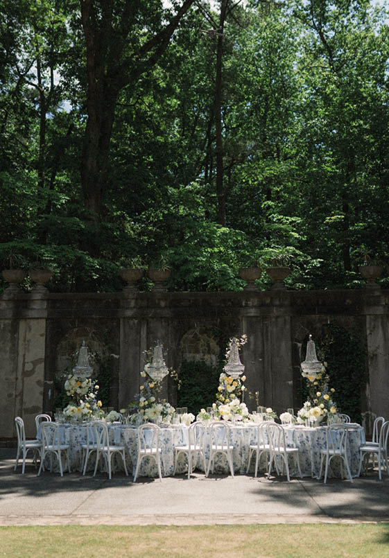 A white table with a floral centerpiece and chairs around it. Description generated by AI