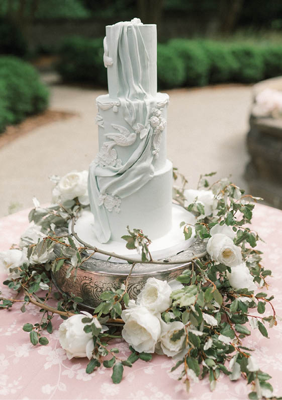 A white cake with a statue on top. Description generated by AI