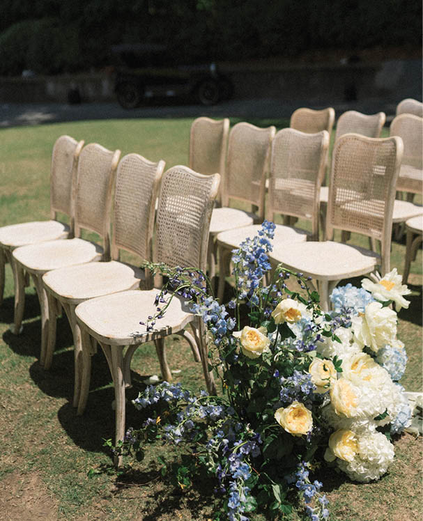 A flower arrangement in a field with chairs. Description generated by AI