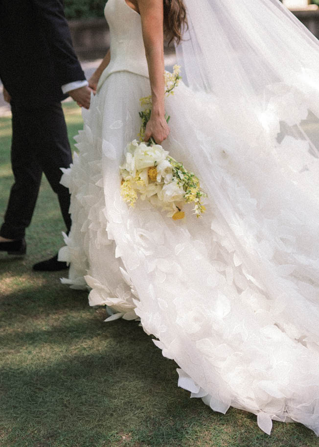 A bride in a white dress with a veil and a bouquet of flowers. Description generated by AI