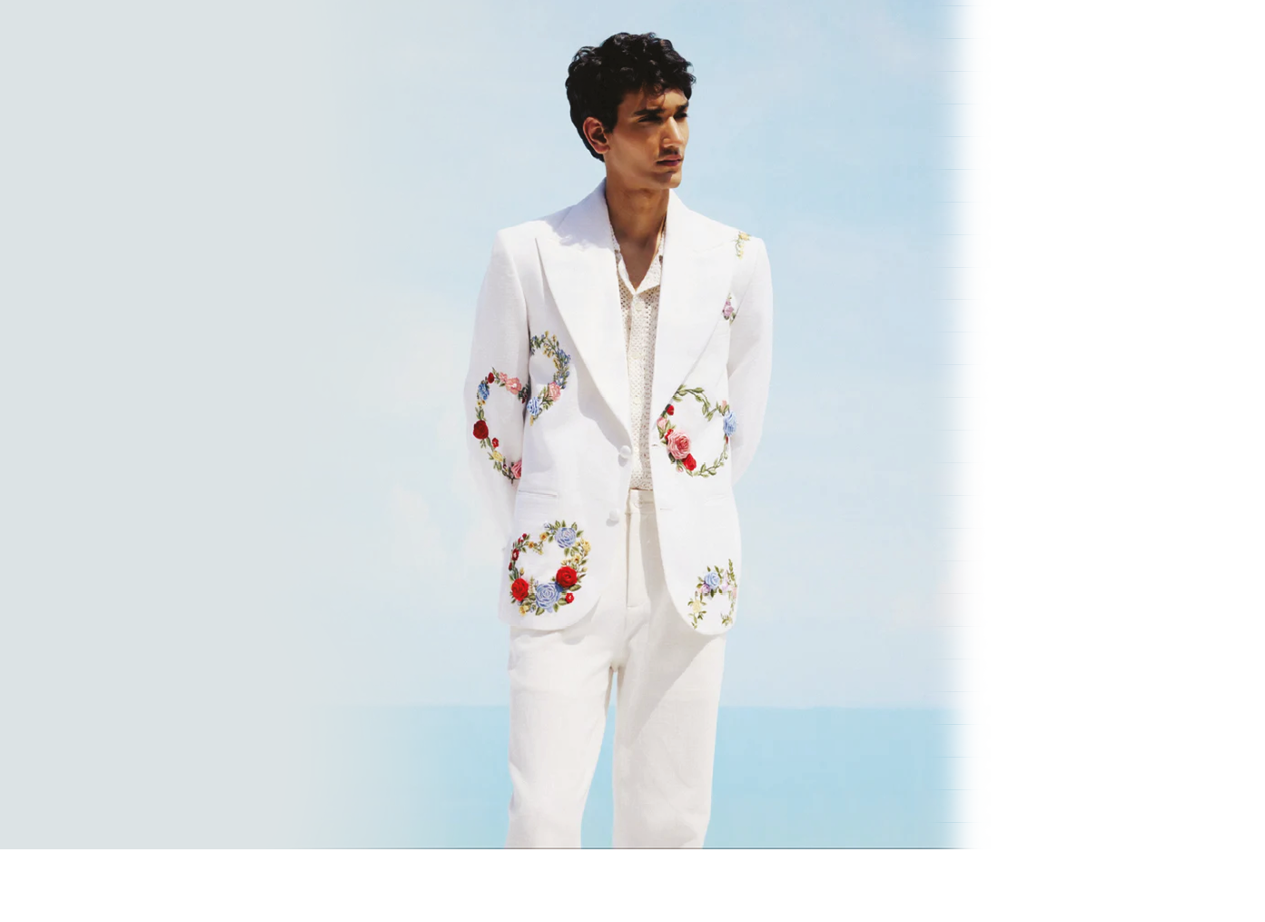 A man wearing a white suit with a floral pattern. Description generated by AI