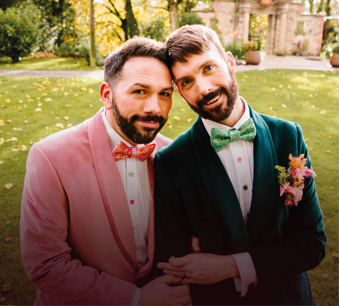 Two men wearing pink and green jackets and ties. Description generated by AI