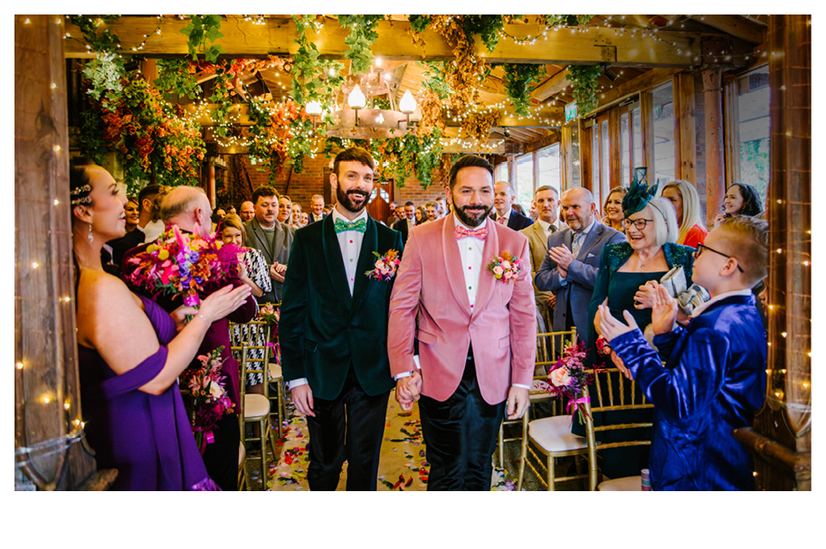 Two men wearing pink jackets and ties. Description generated by AI