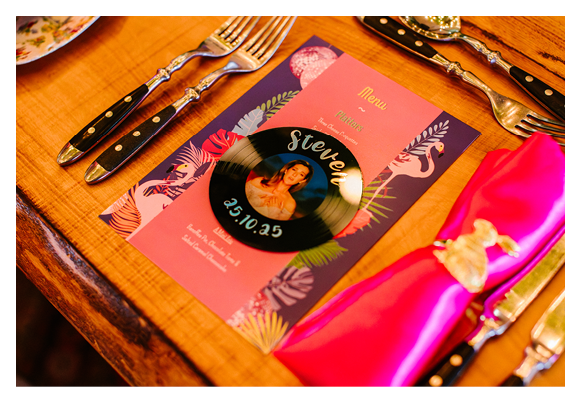 A table with a pink tablecloth and silverware. Description generated by AI