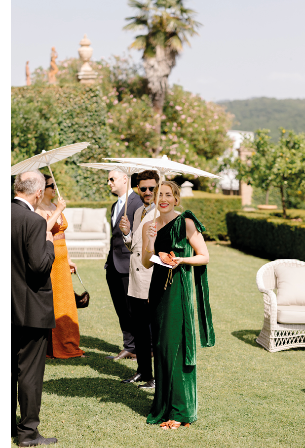 A woman in a green dress is standing in a field. Description generated by AI