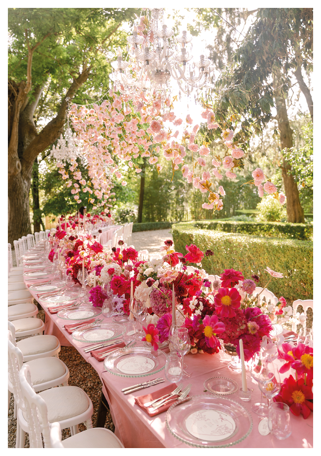 A table with a pink tablecloth and white chairs. Description generated by AI