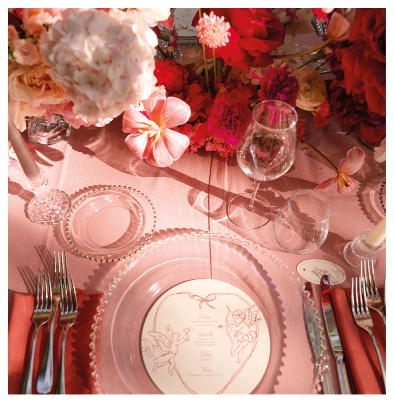 A table with a pink tablecloth, a plate with a napkin, a fork, a knife, and a spoon. Description generated by AI