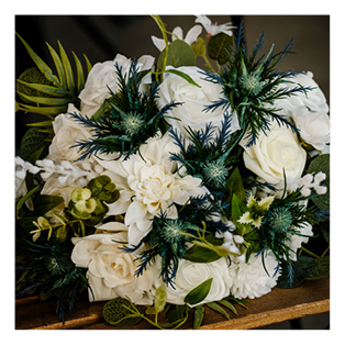 A bouquet of white and blue flowers with green leaves. Description generated by AI
