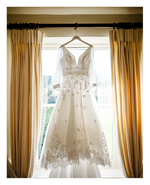 A white wedding dress hangs in a closet. Description generated by AI