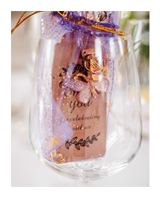 A wine glass with a purple and gold label. Description generated by AI